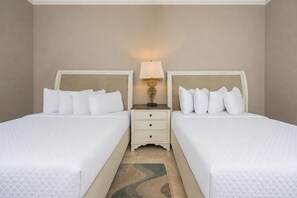 A hotel room with two beds, a nightstand with a lamp, and a patterned rug. - The Oasis 1409 Formerly Phoenix West Ii 1409 3 Bedroom Condo (Orange Beach)