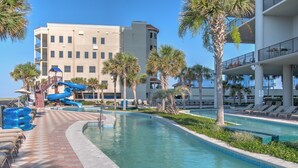 A pool area with a water slide, lounge chairs, and palm trees. - The Oasis 1409 Formerly Phoenix West Ii 1409 3 Bedroom Condo (Orange Beach)