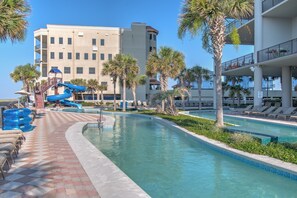 A pool area with a water slide, lounge chairs, and palm trees. - The Oasis 1409 Formerly Phoenix West Ii 1409 3 Bedroom Condo (Orange Beach)