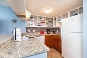 Een keuken met een magnetron, koffiezetapparaat en een koelkast.