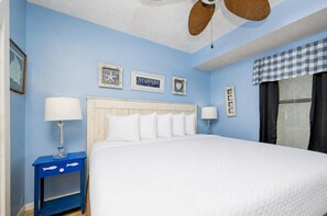 A hotel room with a large bed, two bedside tables, a ceiling fan, and wall decorations. - Island Winds East 204 1 Bedroom Condo (Gulf Shores)