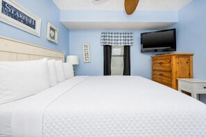 Ein Hotelzimmer mit einem Bett, einem Fernseher, einer hölzernen Kommode und einer Wand mit einem gerahmten Schild.