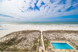 A beach with a swimming pool, sandy dunes, and a clear sky. - Island Winds East 604 1 Bedroom Condo (Gulf Shores)