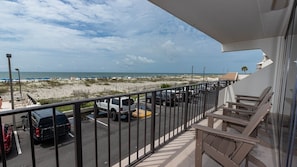 A balcony with a view of a beach and parked cars. - Island Winds East 109 2 Bedroom Condo (Gulf Shores)
