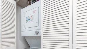 A compact, white laundry room with a built-in washer and dryer, featuring a control panel with various settings. - Island Winds East 109 2 Bedroom Condo (Gulf Shores)