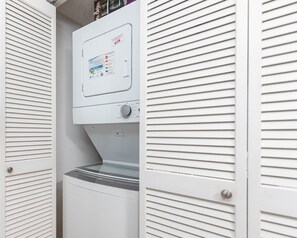 A compact, white laundry room with a built-in washer and dryer, featuring a control panel with various settings. - Island Winds East 109 2 Bedroom Condo (Gulf Shores)