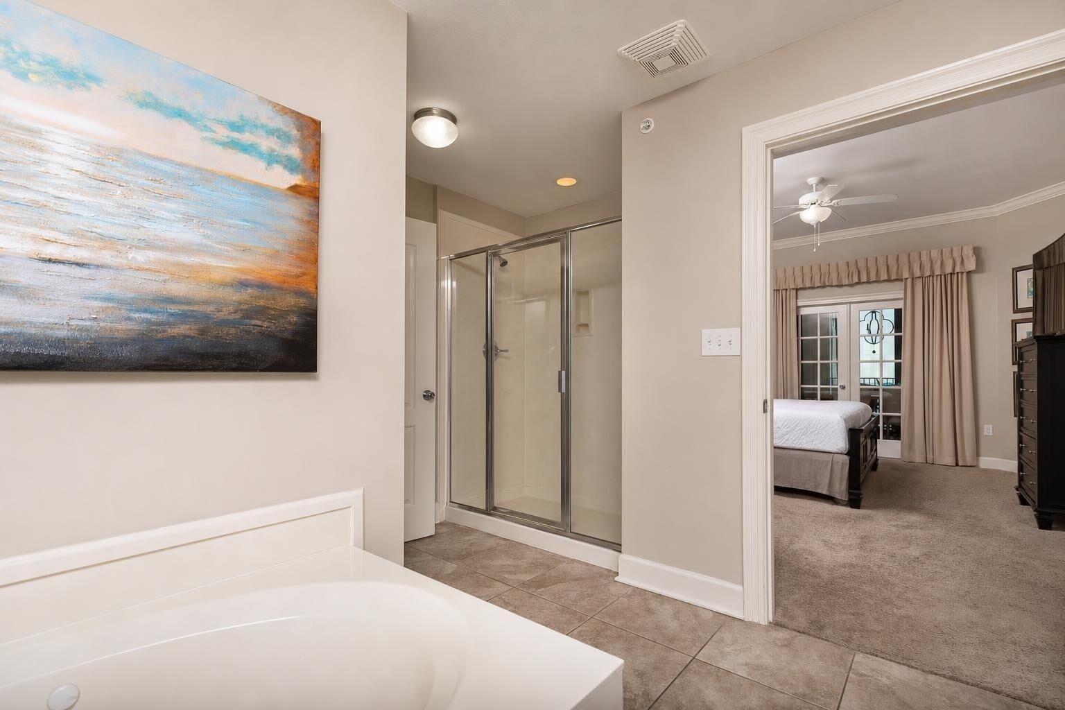 A bathroom with a bathtub, a glass shower enclosure, and a painting on the wall.
