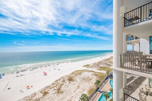 Blick auf den Strand vom Balkon mit Pool und Sitzgelegenheit im Freien.