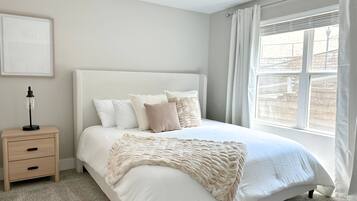 A bedroom with a bed, a nightstand, a ceiling fan, and a window with curtains.