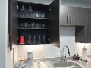 A kitchen with a built-in coffee maker, a sink, and a cabinet with glassware. - Newly Remodeled Condo Minutes to UA w/ 2 King Beds & Brand New Furniture (Tuscaloosa)