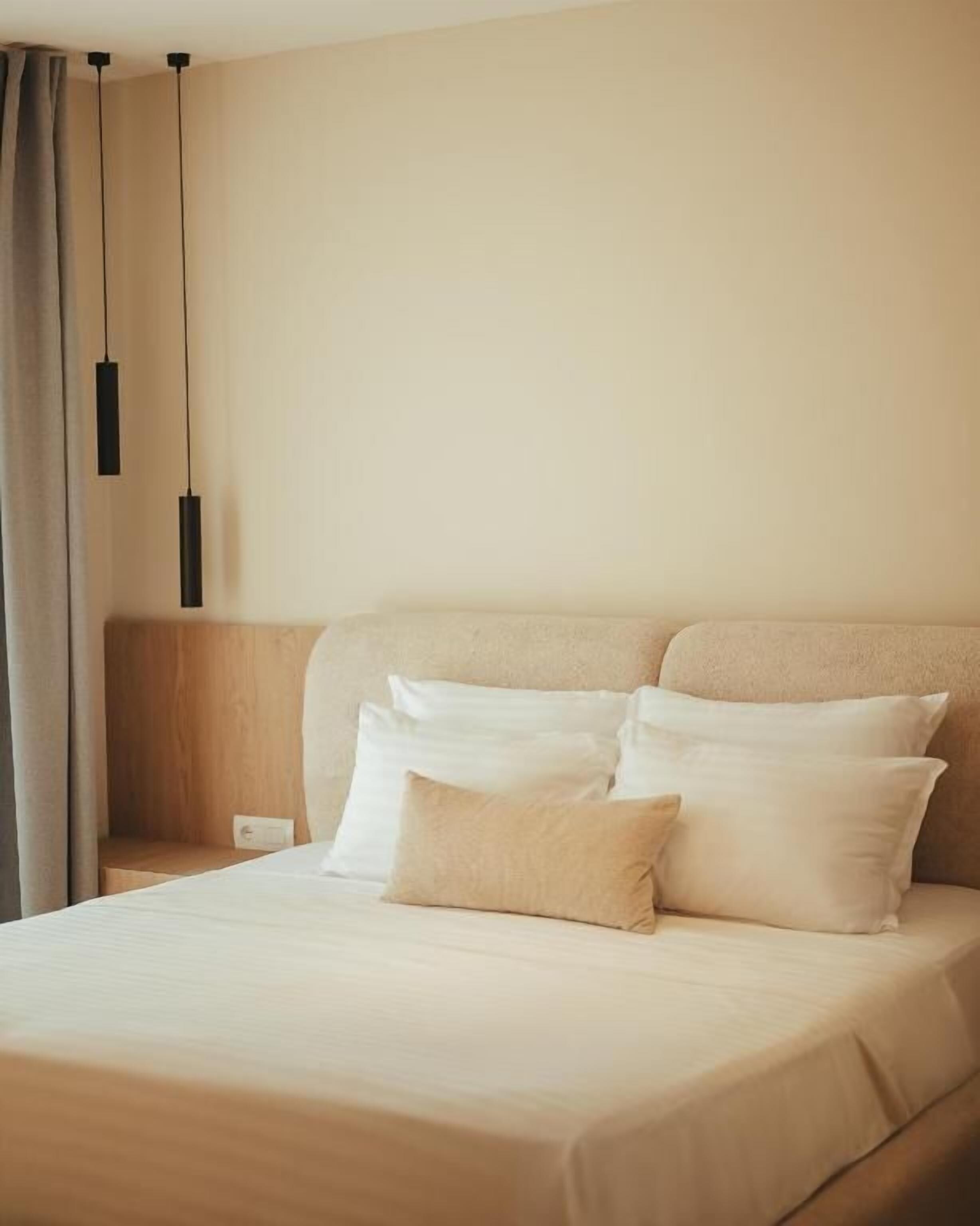 Una habitación de hotel con una cama, almohadas, una mesita de noche y una lámpara.
