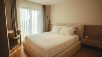 A bedroom with a large bed, a chair, and a window with curtains.