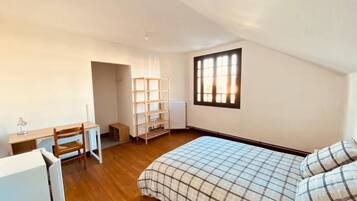 Un dormitorio con cama, escritorio y estantería.