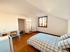 A bedroom with a bed, a desk, and a shelving unit. - Chambre privative dans maison partagée  (FRANCE)
