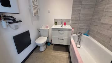Een badkamer met toilet, wastafel en bad.