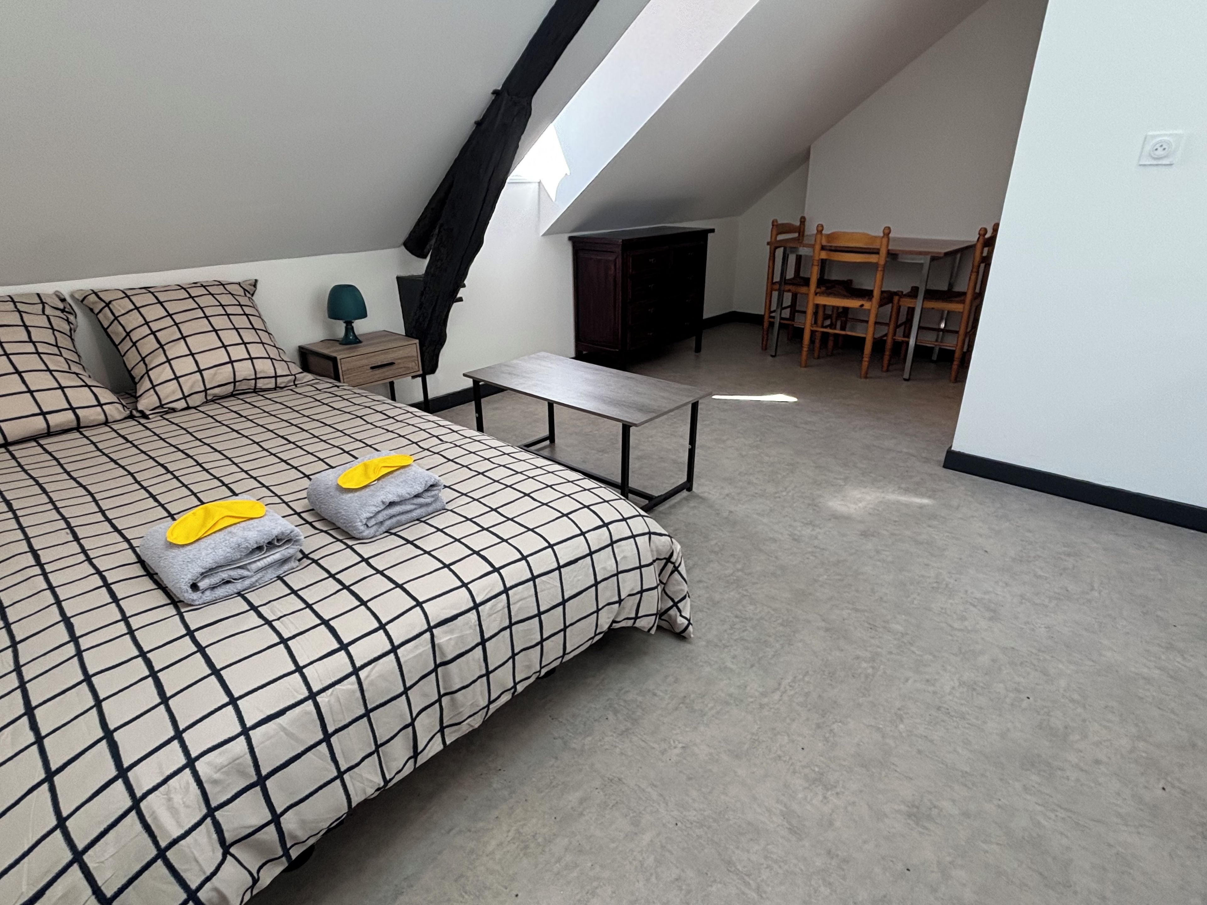 Un dormitorio con cama, mesita de noche, mesa y silla.
