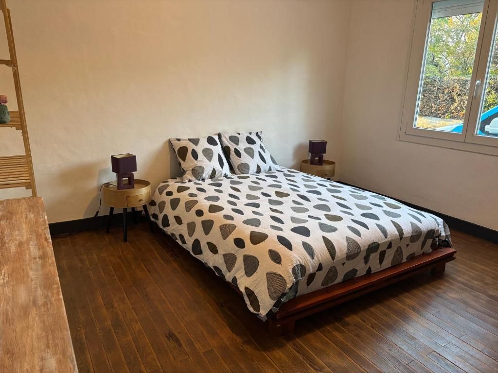 Un dormitorio con cama, dos mesitas de noche, suelo de madera y ventana con vistas.
