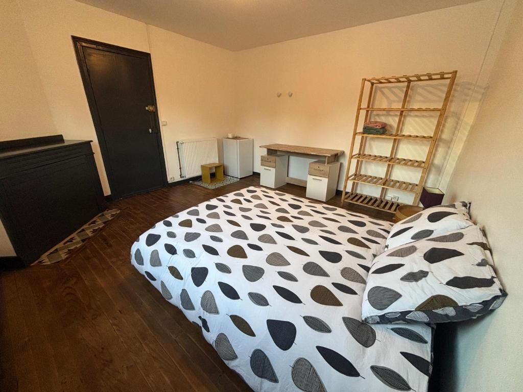 Een slaapkamer met een bed, een bureau, een radiator en een kledingkast.