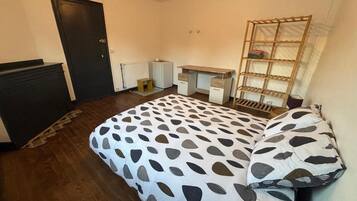 Een slaapkamer met een bed, een bureau, een radiator en een kledingkast.