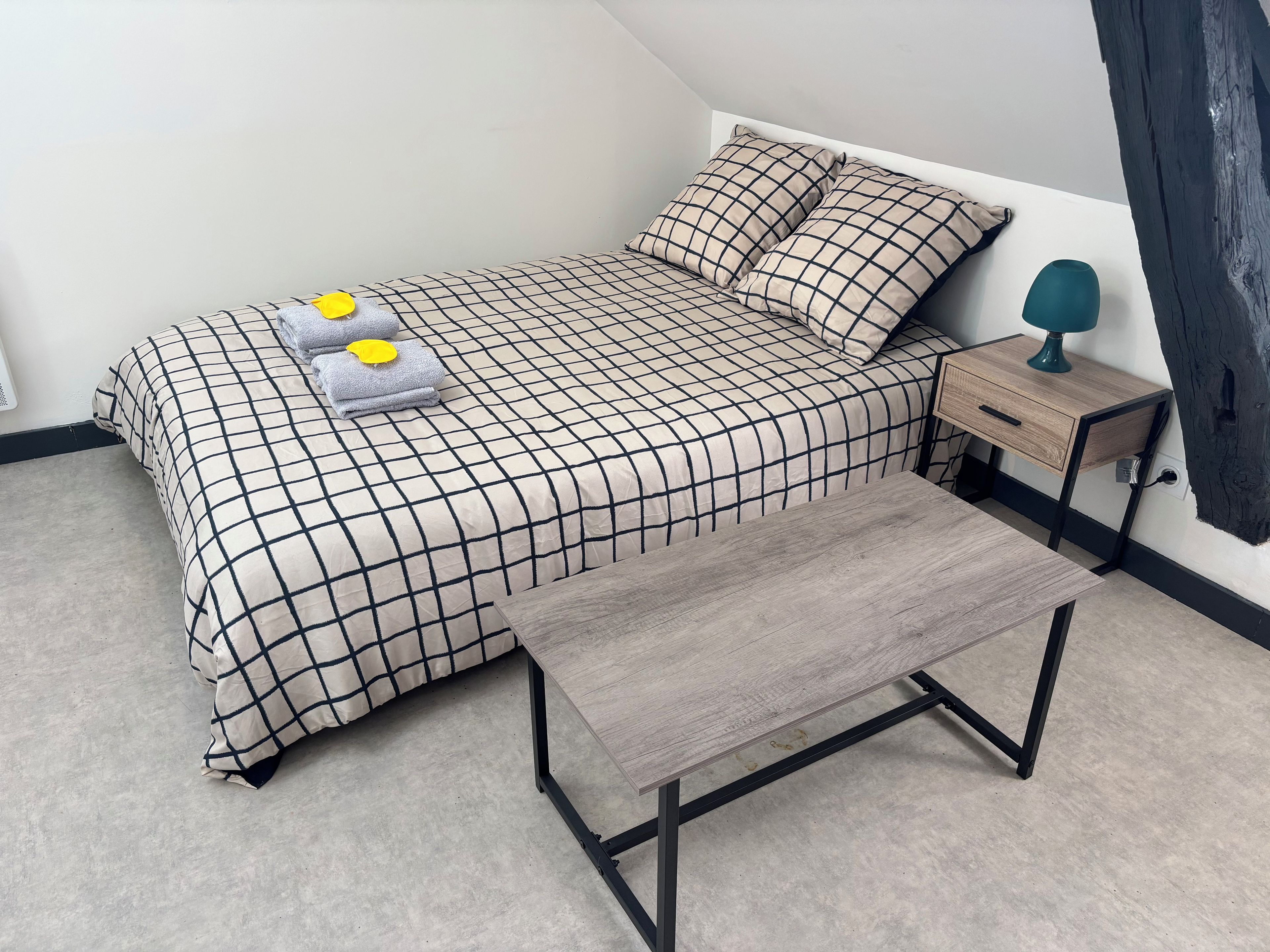 Une chambre à coucher avec un lit, un banc, une table de chevet et une lampe.