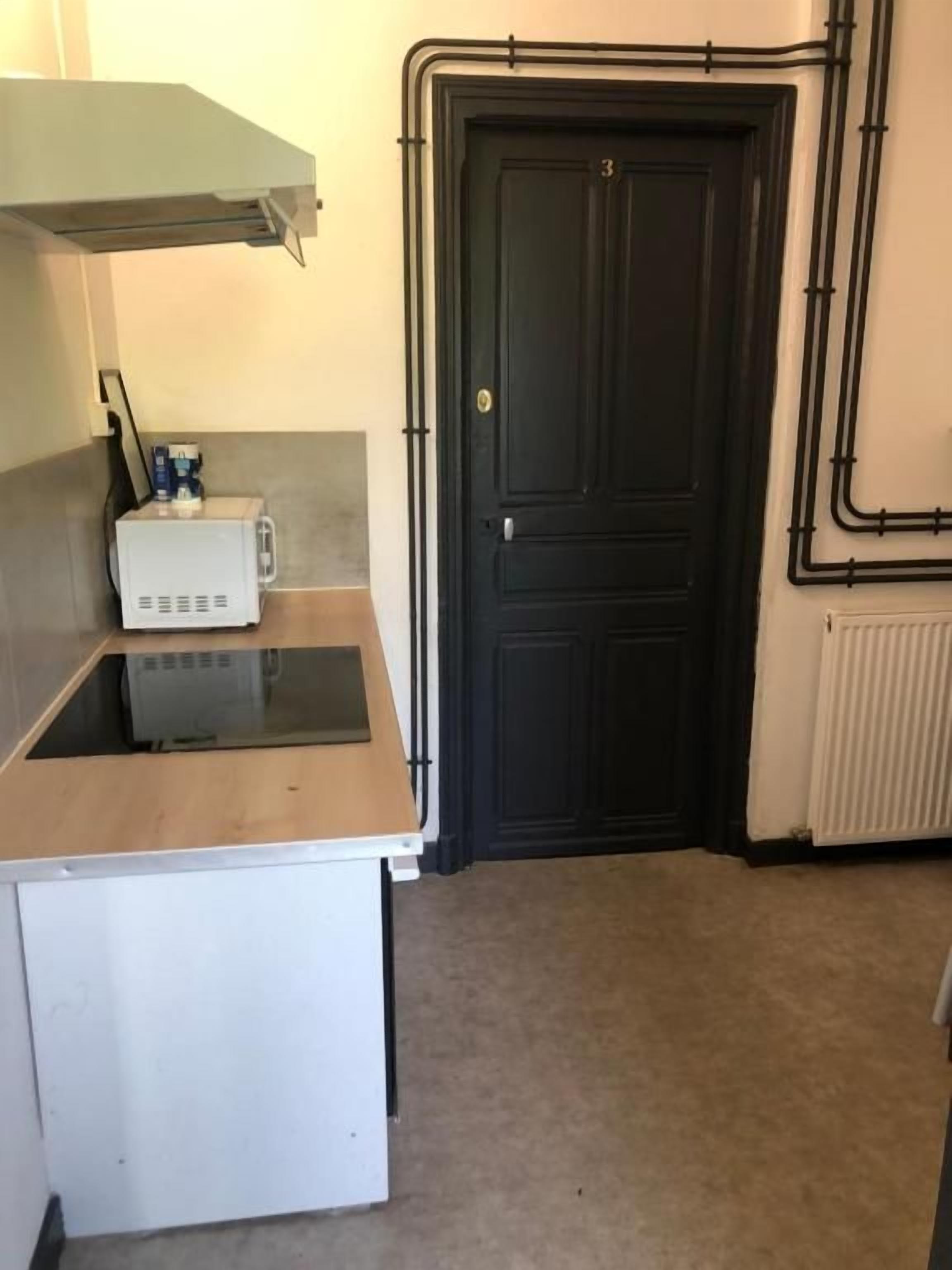 A compact kitchen with a microwave, a small refrigerator, and a black door.