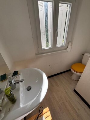 A bathroom with a white sink, a yellow toilet, and a window above the sink. - Chambre privative dans maison partagée  (FRANCE)