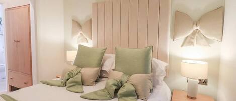 A hotel room with a bed, bedside tables, a nightstand, and a wardrobe.