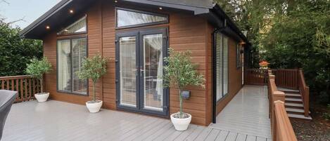 A modern wooden cabin with large windows and a deck.