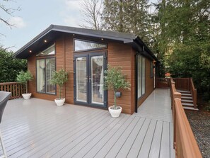 Una cabaña moderna de madera con ventanas grandes y una terraza.