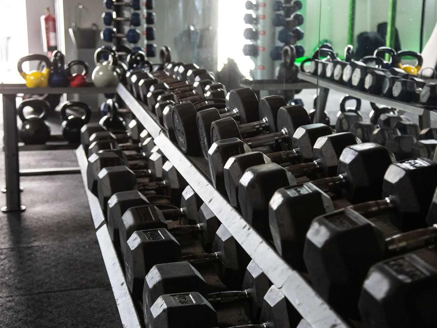 Ein Fitnessraum mit Reihen von Kurzhanteln und Kettlebells.