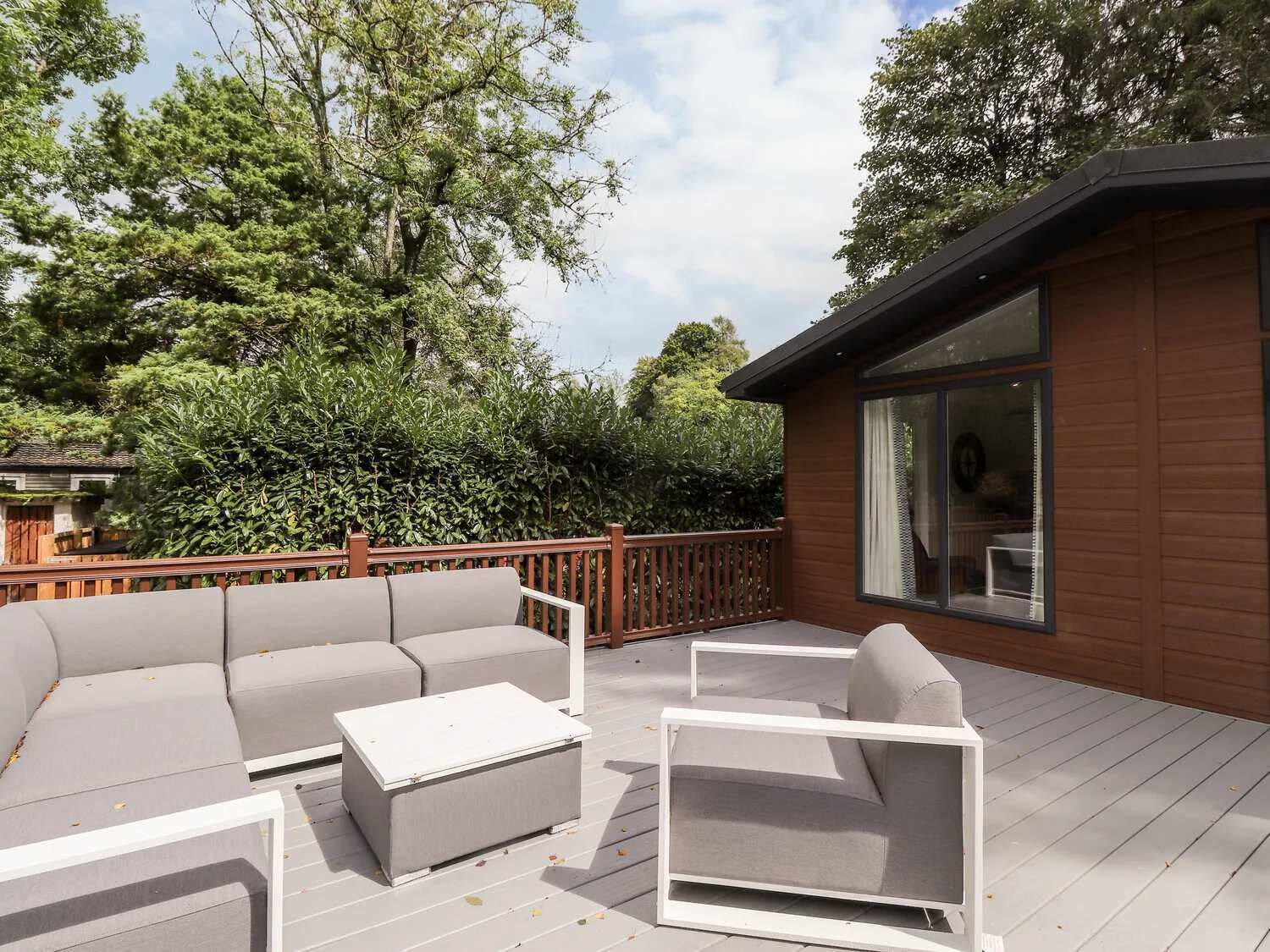 Une terrasse extérieure avec un ensemble de canapés, une table basse et une rambarde en bois.