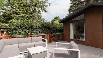Une terrasse extérieure avec un ensemble de canapés, une table basse et une rambarde en bois.