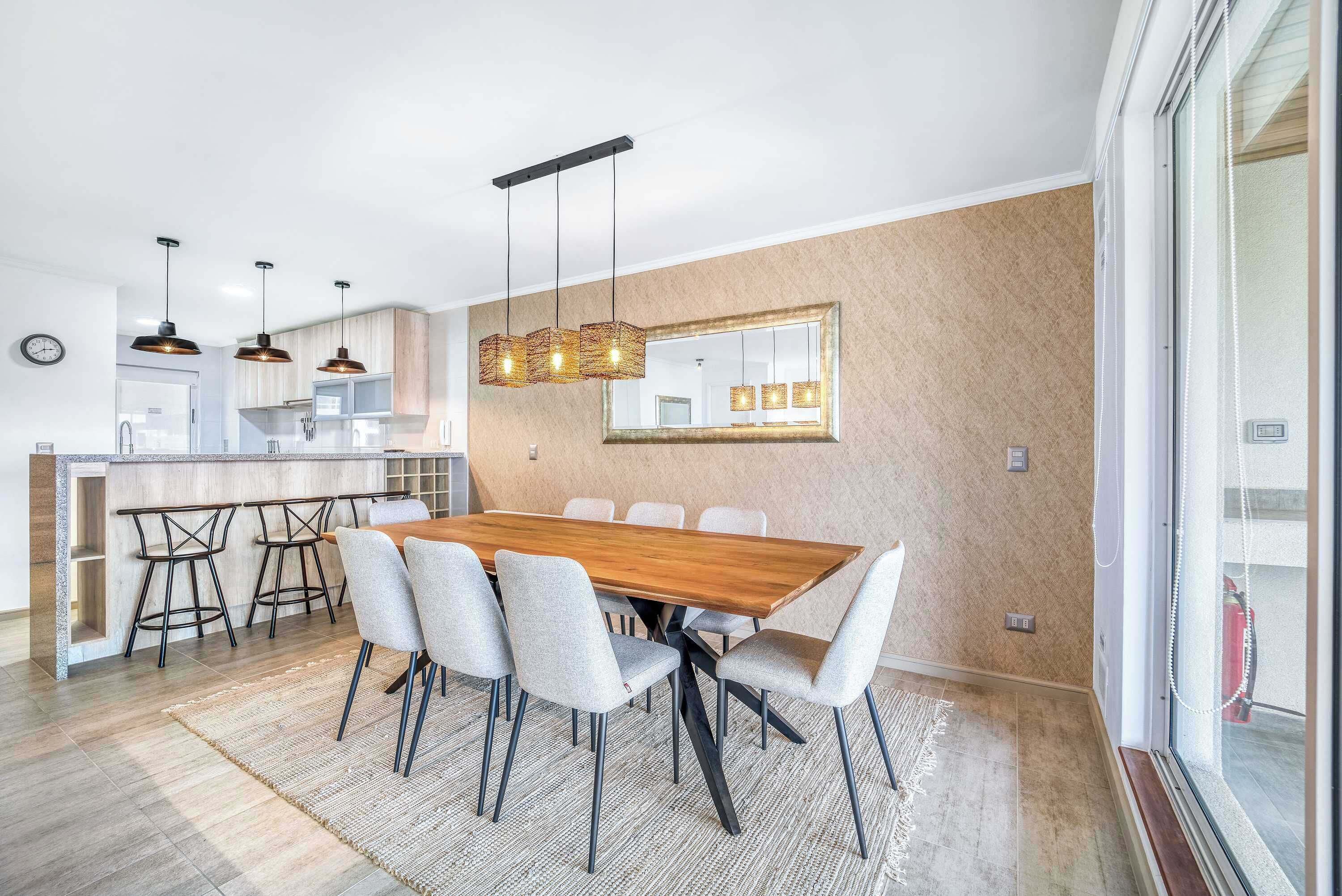 A modern kitchen with a central island, bar stools, and pendant lighting.