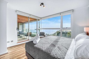 A modern bedroom with a large bed, a view of the city, and a balcony with outdoor furniture. - Vista El Yeco | Vista al mar y acceso a playa (Algarrobo)