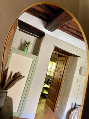 An arched doorway leading to a room with a tiled floor, a wooden door, and a potted plant. - La Salvia • 1864 Stone House by the Lima River (Bagni di Lucca)