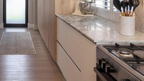 A kitchen with a marble countertop, a gas stove, and a set of wooden cabinets.