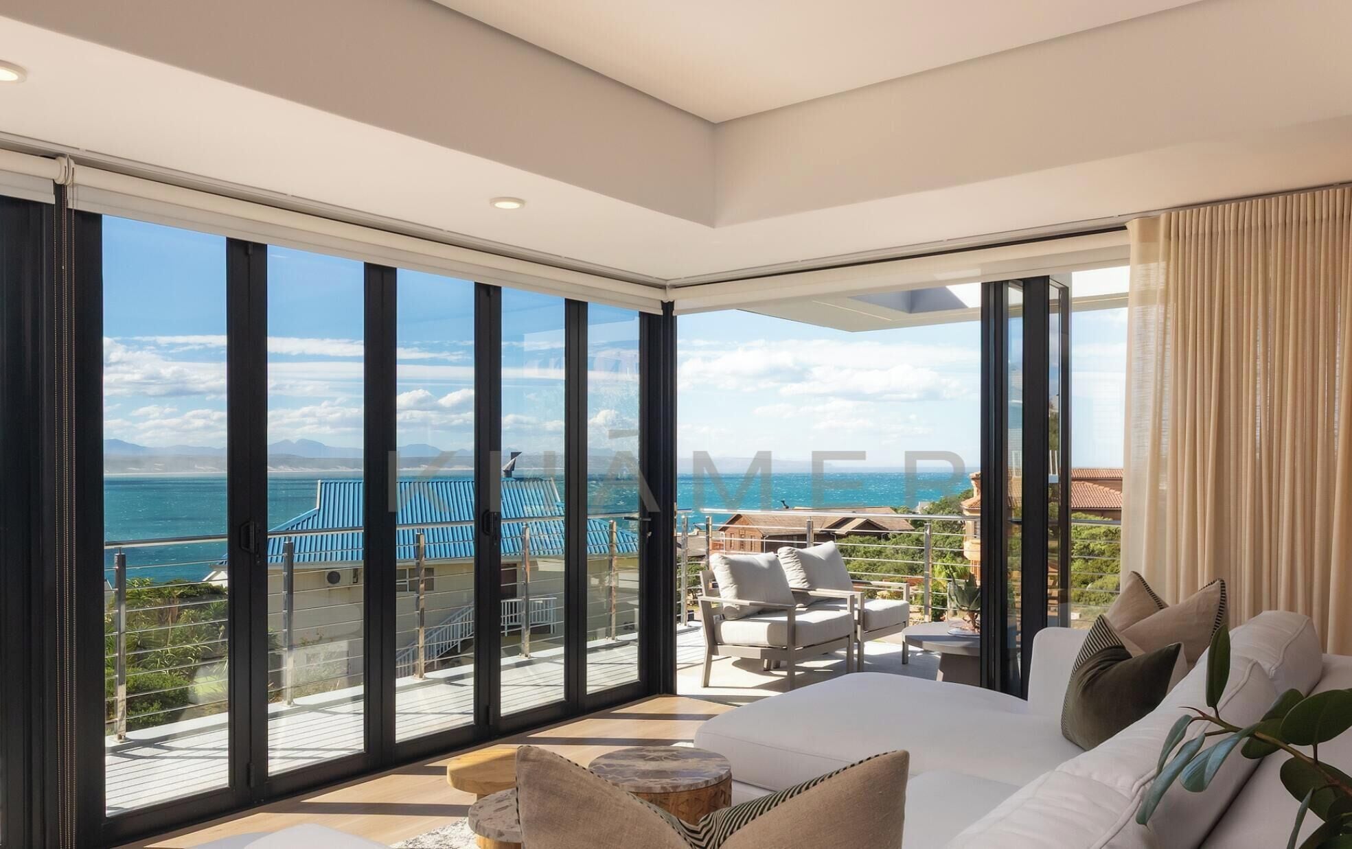 A spacious bedroom with a large bed, a view of the sea, and a balcony with outdoor seating.