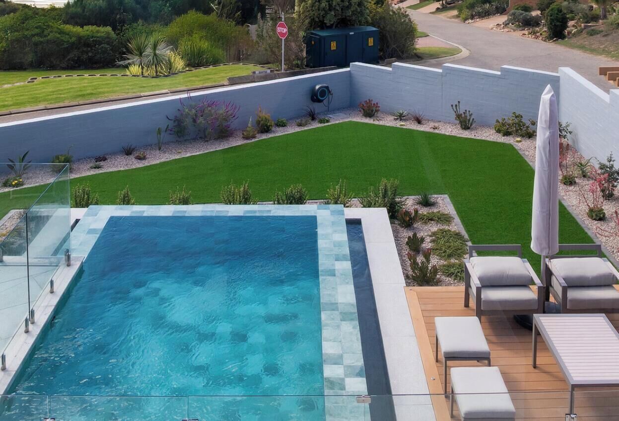 Ein Schwimmbecken mit Blick auf einen angelegten Garten und einem Verkehrsschild im Hintergrund.