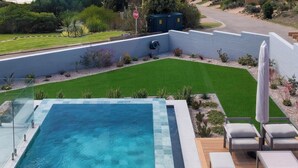 A swimming pool with a view of a landscaped garden and a stop sign in the background.