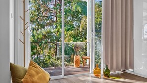 Et værelse med en skydedør, der fører ud til en balkon med udsigt over grønne områder.