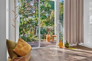 Ein Zimmer mit einer Schiebetür zu einem Balkon mit Blick auf Grünflächen.