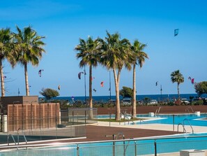 A pool area with palm trees and a clear sky. - LOLA Beachfront Garden Apartment | Pools, Direct Beach Access, and Family-Friendly (Torremolinos)