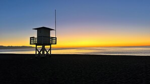 A lifeguard tower on a beach at sunset. - LOLA Beachfront Garden Apartment | Pools, Direct Beach Access, and Family-Friendly (Torremolinos)