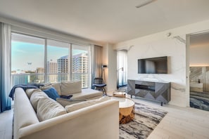 A modern living room with a sofa, a round coffee table, a TV, and a fireplace. - 3 High-rise Beach Condos! Views, Resort Perks (Fort Lauderdale)