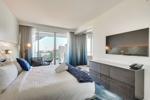 Una camera d'albergo moderna con un letto grande, una scrivania, una sedia, una TV e vista sulla città.