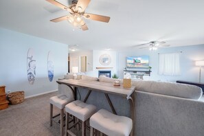 A modern living room with a bar area, a ceiling fan, and a television. - Saltwater Revival - Stay with Seaside Vacations! (Chincoteague Island)