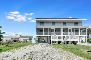 A two-story beachfront building with a covered porch and a staircase leading to the upper level. - Saltwater Revival - Stay with Seaside Vacations! (Chincoteague Island)