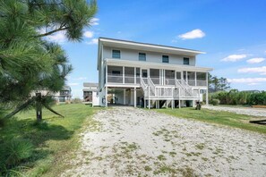 A two-story house with a covered porch and a gravel driveway. - Saltwater Revival - Stay with Seaside Vacations! (Chincoteague Island)