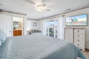 A bedroom with a bed, a ceiling fan, a television, and a view of the outside. - Saltwater Revival - Stay with Seaside Vacations! (Chincoteague Island)