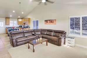 A spacious living room with a large leather sectional sofa, a wooden coffee table, and a view of the kitchen in the background. - Patio & Mtn Views! Group Getaway in South Jordan (South Jordan)
